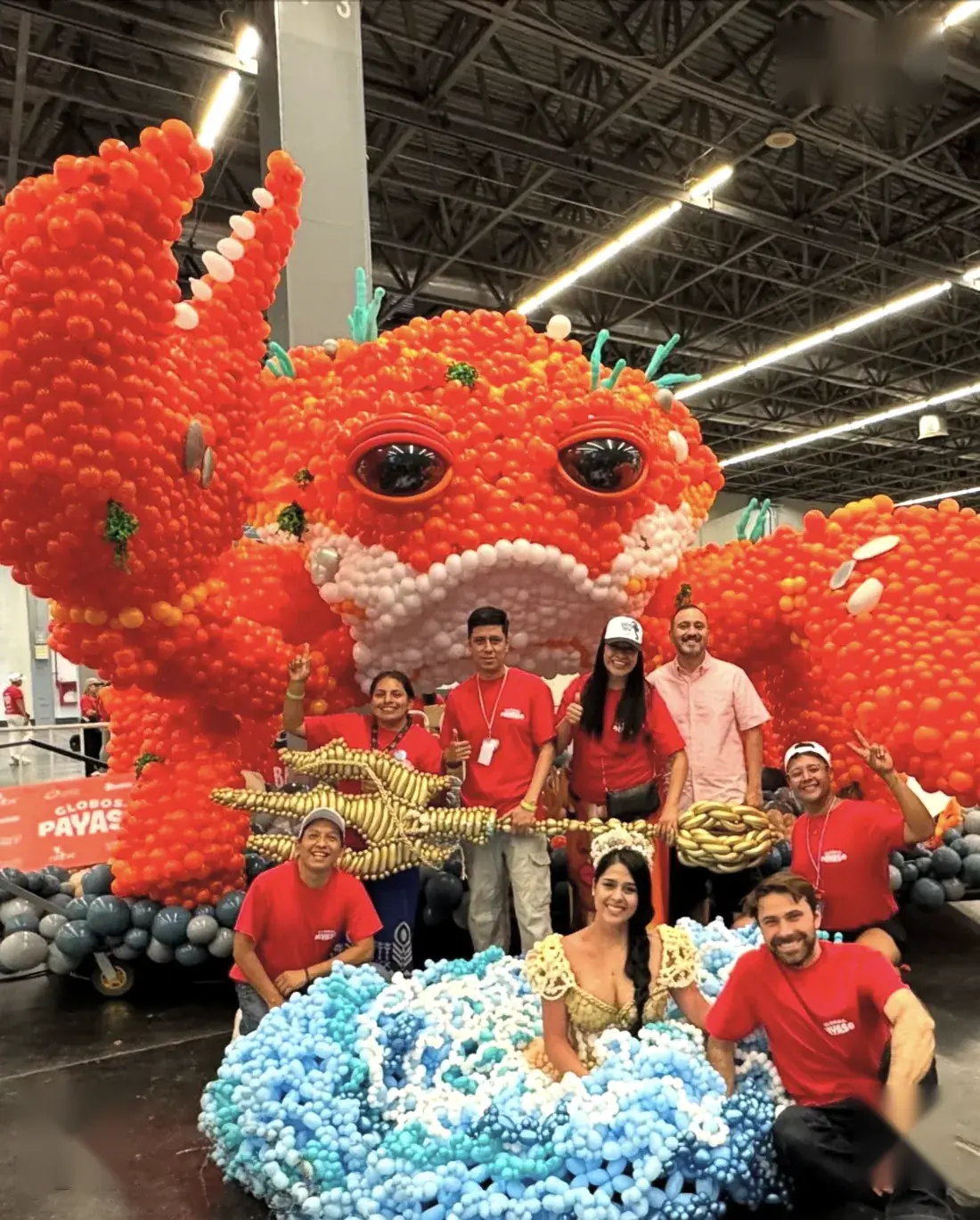 Equipo de montaje posando frente a la escultura terminada de globos