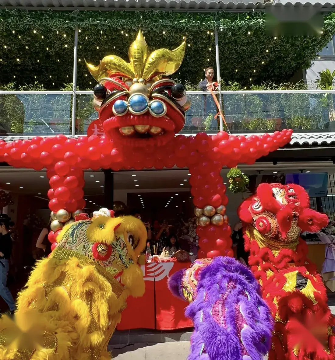 Portal de globos rojos coronado con cabeza de dragón dorada para una inauguración