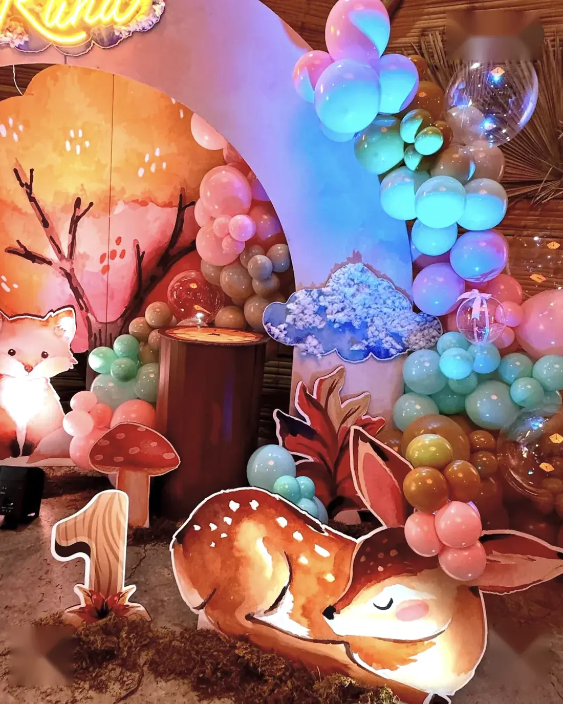 Ambientación de bosque encantado con globos pastel, venado y zorro para un primer año